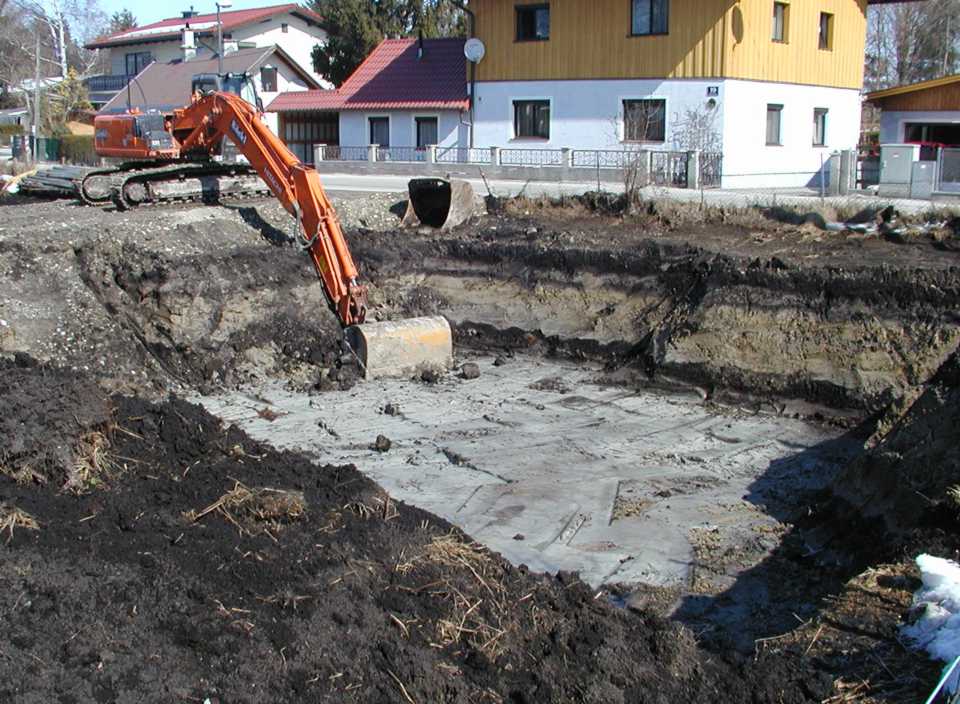 Baugrube mit Humus im Vordergrund